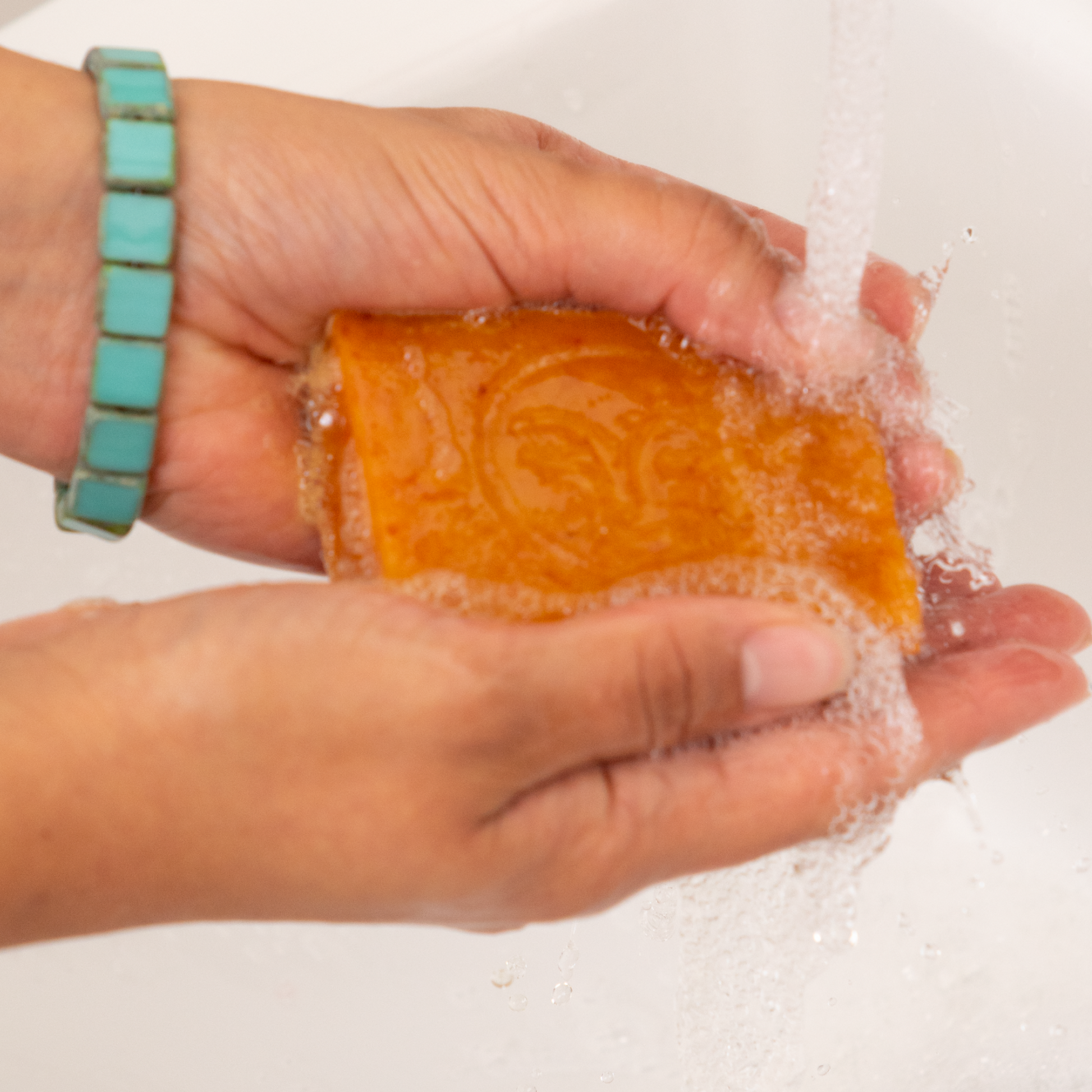 Moon Valley Organics Herbal Soap Bar Hands holding a lathered bar of soap under running water
