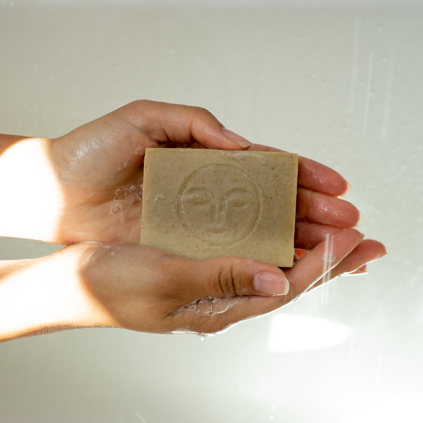 Moon Valley Organics Herbal Soap Bar Hands holding a lathered bar of soap under shower