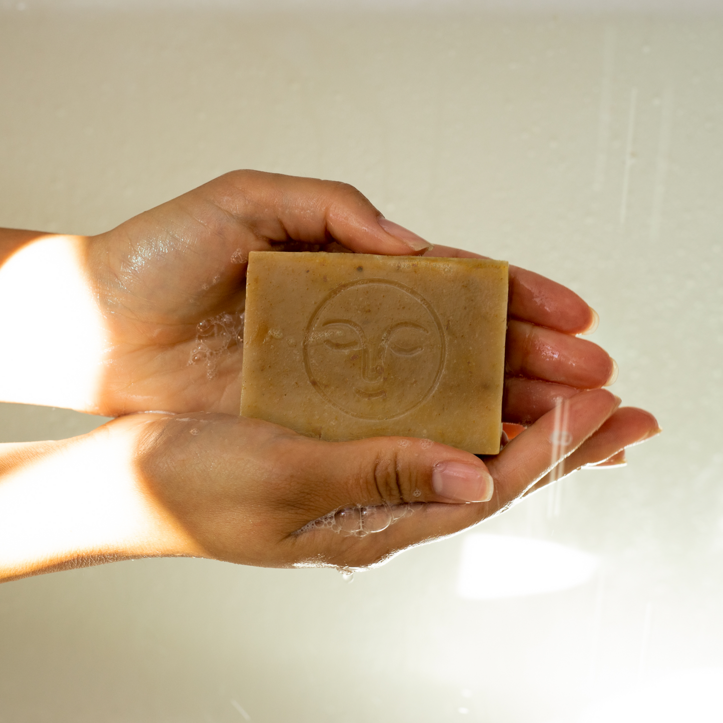 Moon Valley Organics Herbal Soap Bar Hands holding a lathered bar of soap under shower