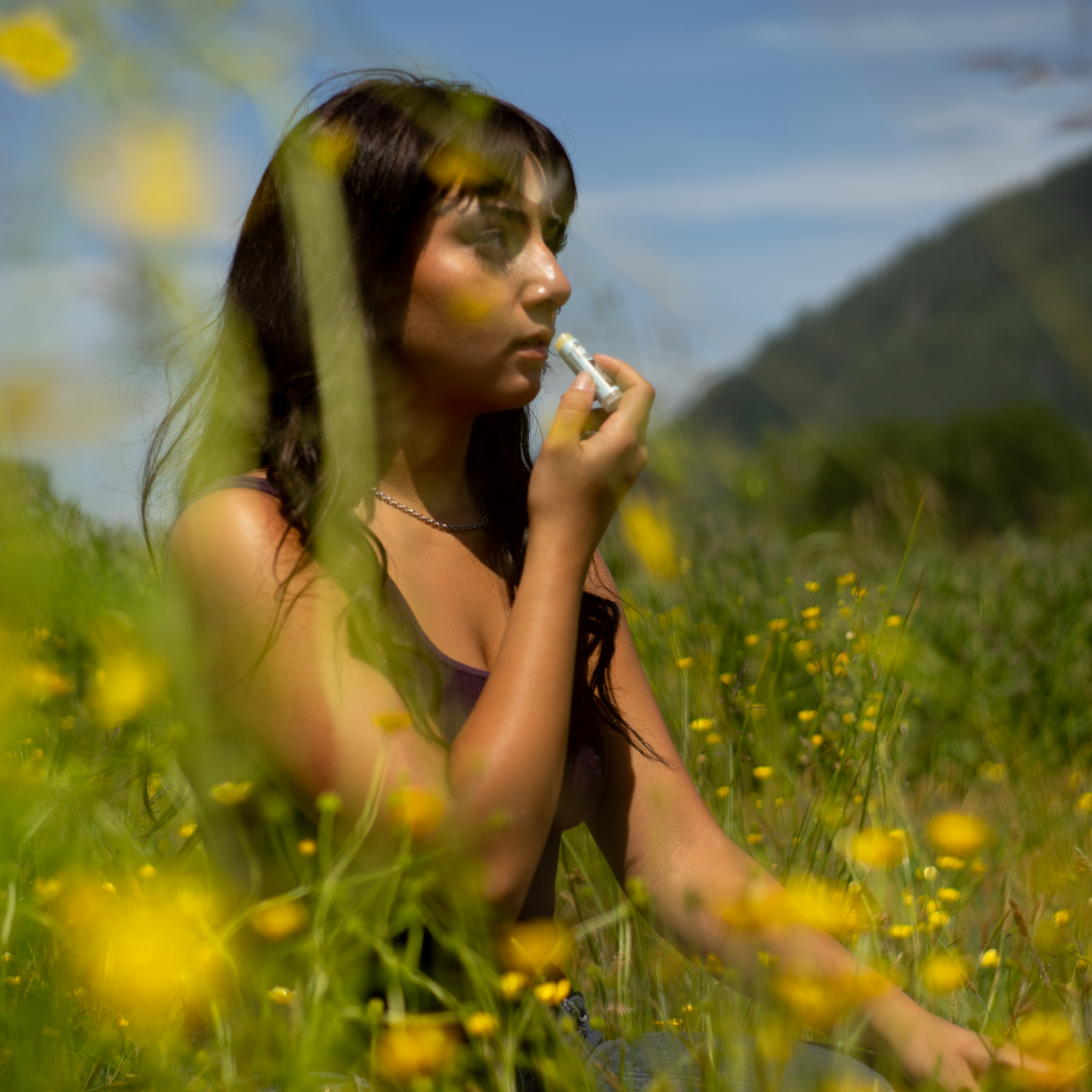 Moon Valley Organics Beeswax Lip Balm Woman in field of flowers applying lip balm to lips