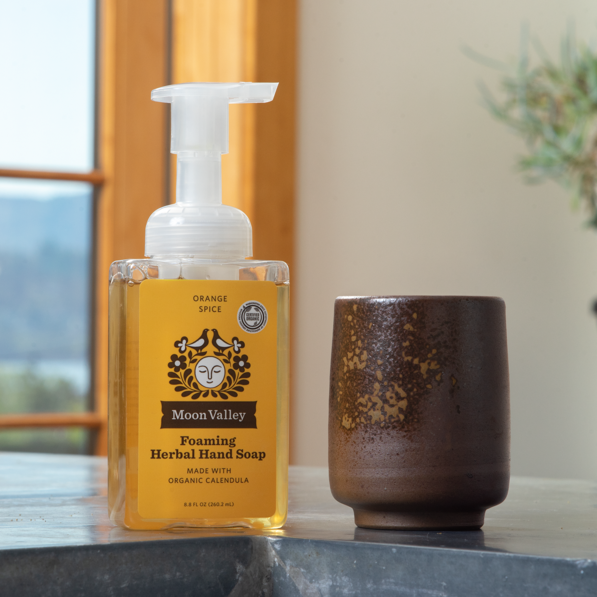 Moon Valley Organics Foaming Herbal Hand Soap Front Dispenser Bottle Orange Spice on a kitchen sink