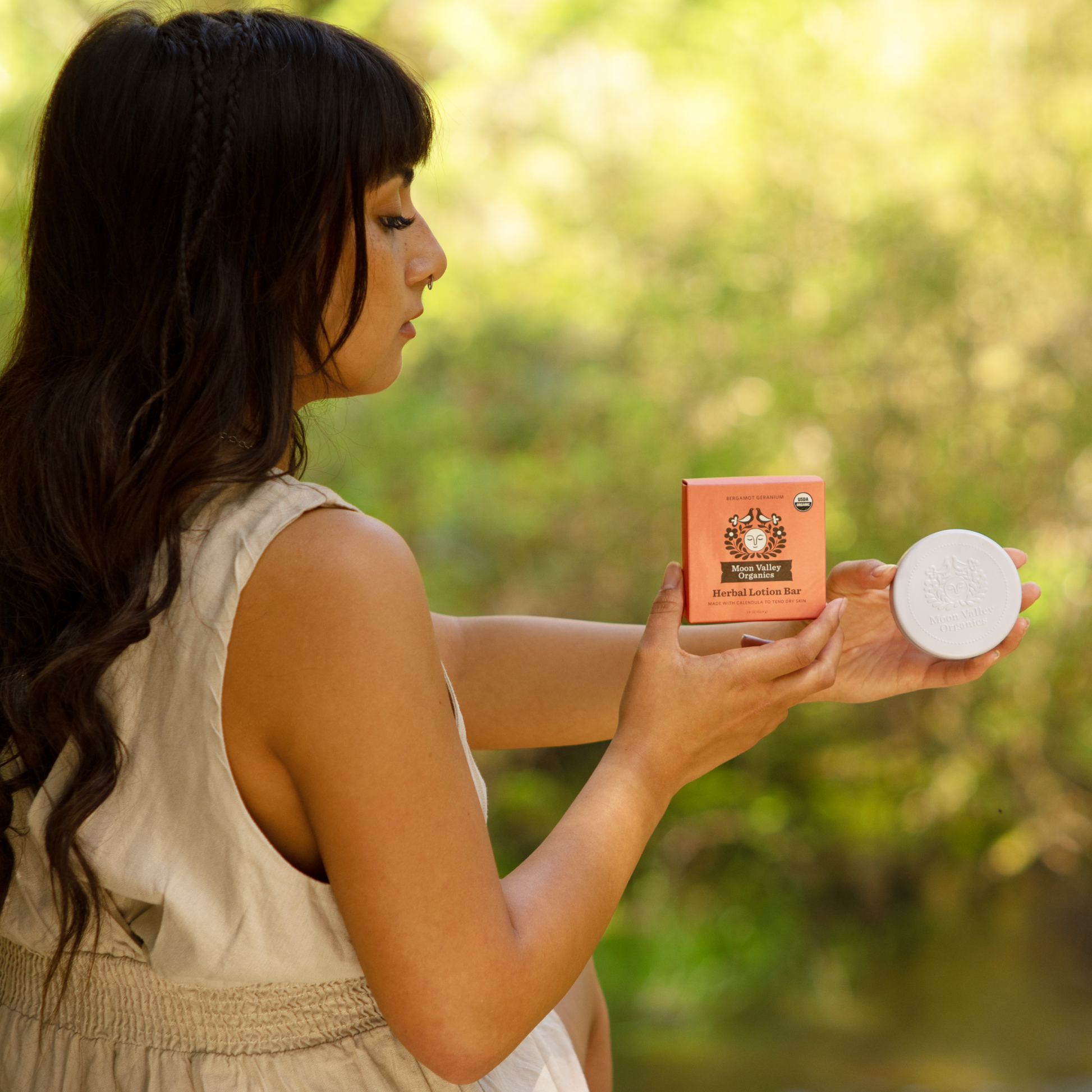 Moon Valley Organics Herbal Lotion Bar Hand Woman holds Bergamot Geranium box and tin