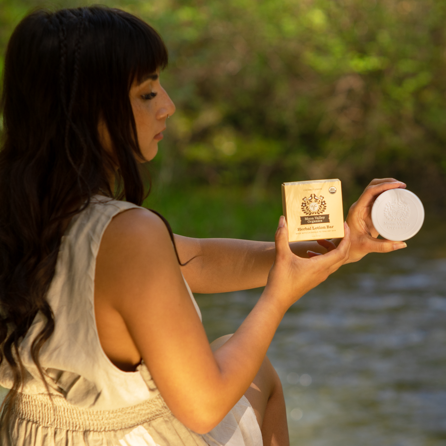 Moon Valley Organics Herbal Lotion Bar Hand Woman holds Coconut Lemon box and tin